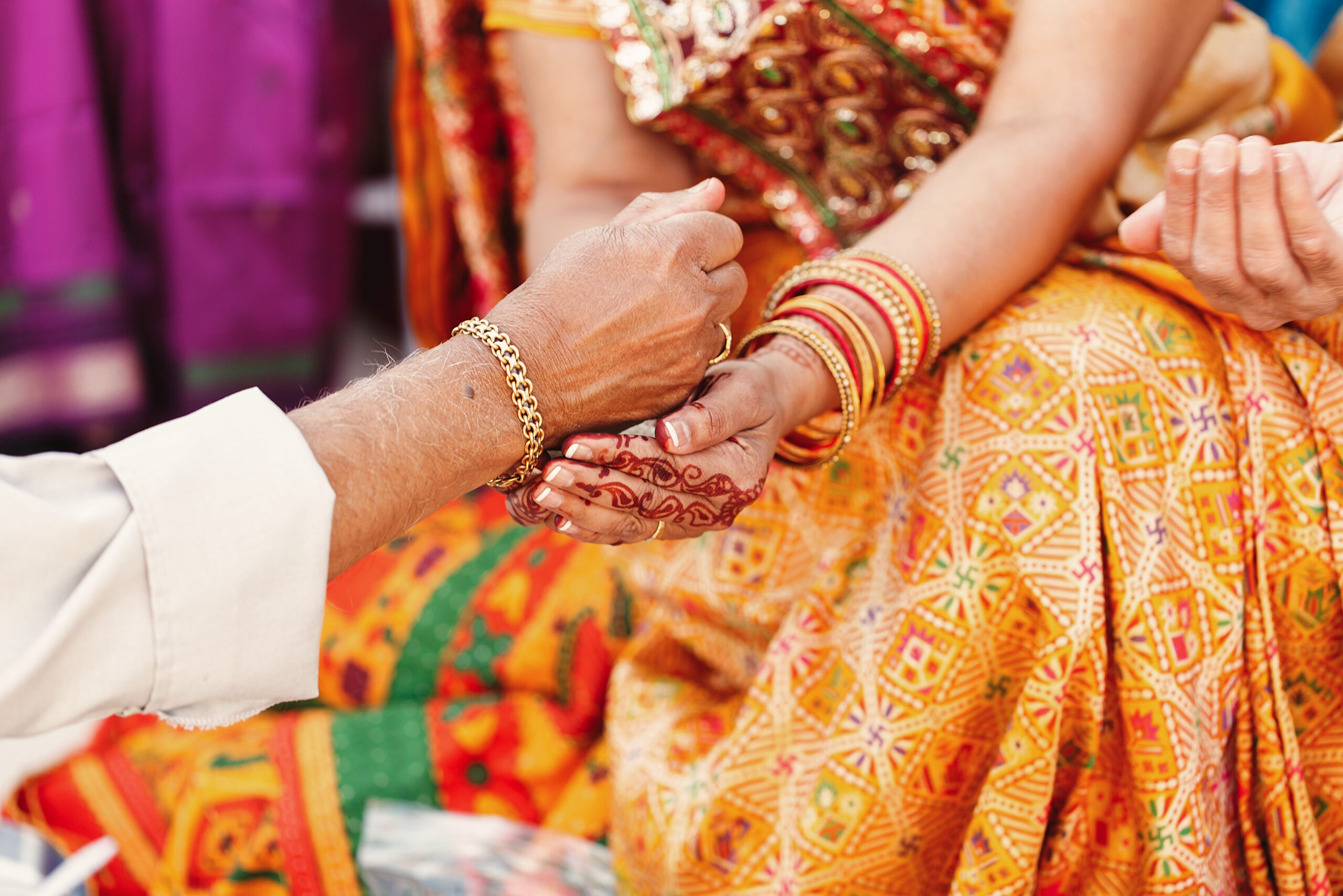 old man pours something in the hands of indian woman dressed in